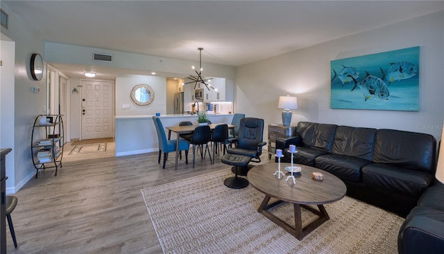 living room featuring a notable chandelier and light wood-type flooring