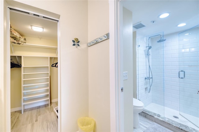 bathroom featuring hardwood / wood-style flooring, toilet, and a shower with door