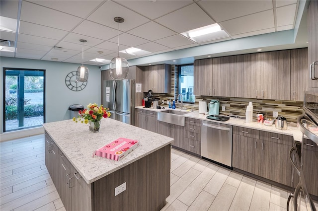 kitchen featuring stainless steel appliances, sink, pendant lighting, light hardwood / wood-style flooring, and a center island