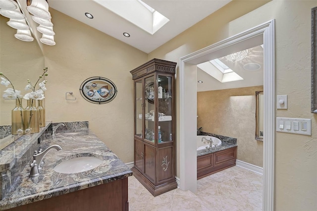 bathroom featuring a bath, vanity, and vaulted ceiling with skylight