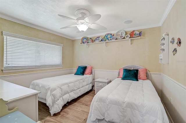 bedroom with a textured ceiling, ceiling fan, wood-type flooring, and ornamental molding