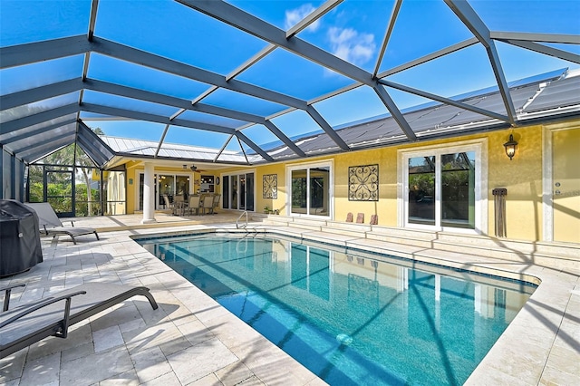 view of swimming pool featuring glass enclosure, ceiling fan, and a patio