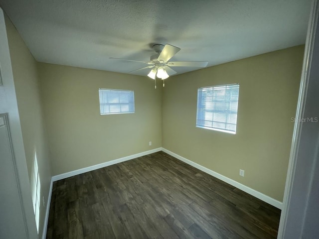 empty room featuring ceiling fan, dark wood-type flooring, and a textured ceiling