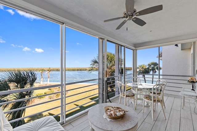 sunroom featuring a water view and ceiling fan