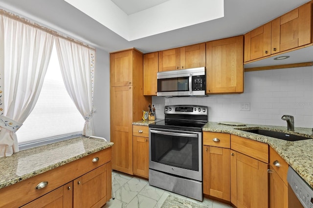 kitchen with decorative backsplash, appliances with stainless steel finishes, light stone counters, and sink