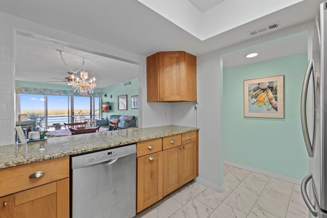 kitchen featuring light stone countertops, kitchen peninsula, pendant lighting, ceiling fan with notable chandelier, and appliances with stainless steel finishes