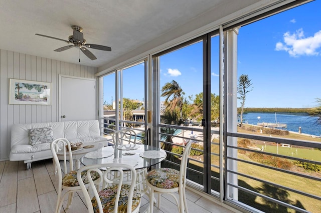 sunroom / solarium featuring a water view and ceiling fan