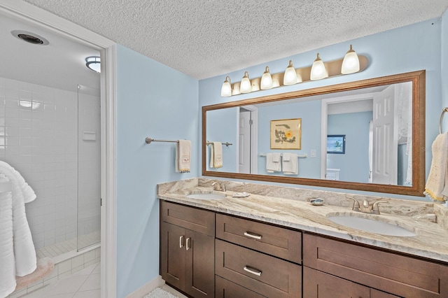 bathroom with tile patterned floors, vanity, a textured ceiling, and tiled shower