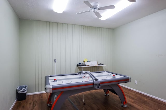 playroom with dark hardwood / wood-style flooring, ceiling fan, and wood walls