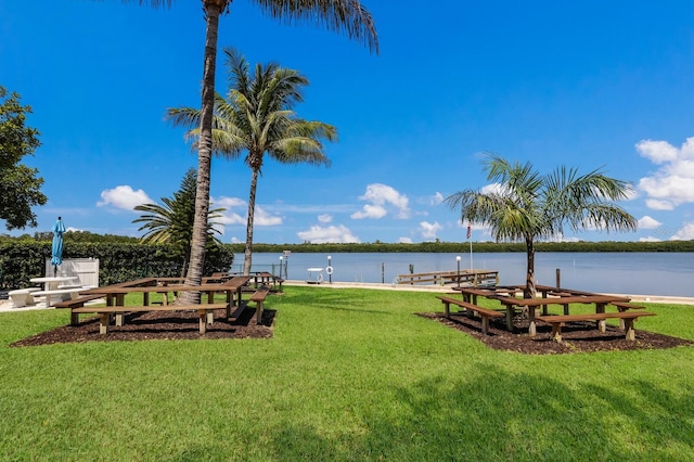 view of community with a lawn, a water view, and a dock