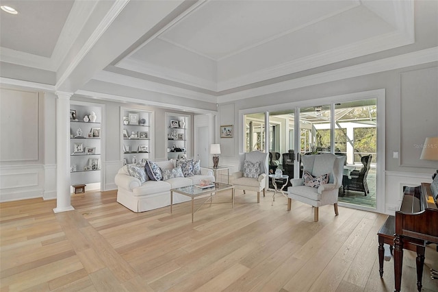 living room featuring built in shelves, light hardwood / wood-style flooring, and ornate columns