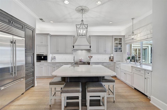 kitchen with a breakfast bar area, a kitchen island with sink, pendant lighting, and appliances with stainless steel finishes