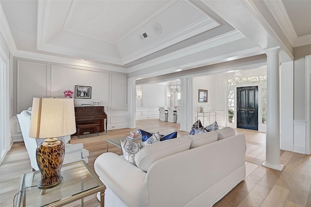 living room featuring hardwood / wood-style flooring, a notable chandelier, ornate columns, and a tray ceiling