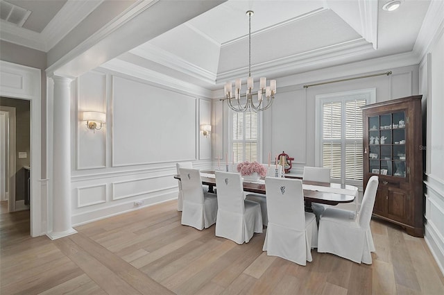 dining room with a raised ceiling, light wood-type flooring, an inviting chandelier, and ornamental molding