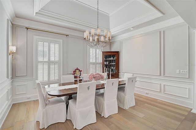 dining area with a chandelier, light hardwood / wood-style floors, crown molding, and a tray ceiling