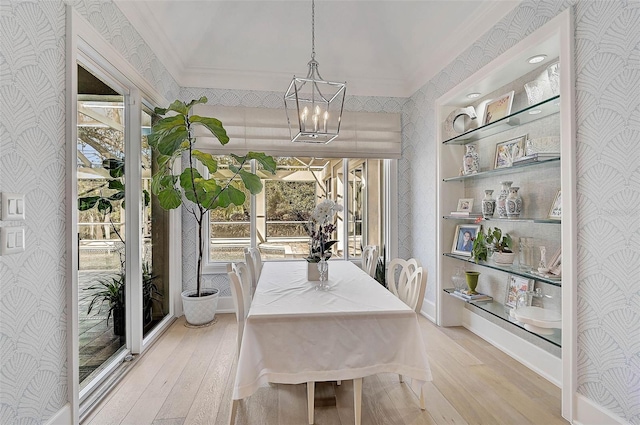 dining area featuring ornamental molding, light hardwood / wood-style flooring, a healthy amount of sunlight, and an inviting chandelier