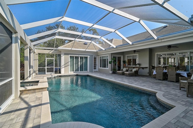 view of swimming pool with glass enclosure, ceiling fan, a patio, and an outdoor hangout area