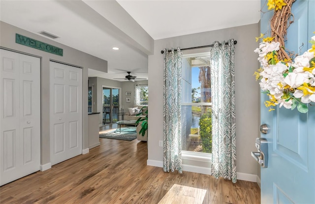 foyer entrance with ceiling fan and light wood-type flooring