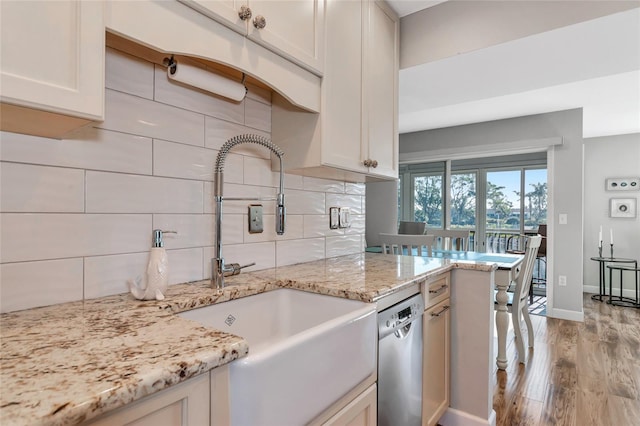 kitchen with dishwasher, sink, decorative backsplash, light wood-type flooring, and light stone counters