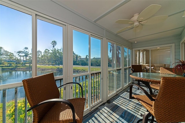 sunroom featuring ceiling fan and a water view