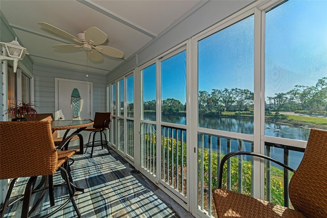 sunroom / solarium with a wealth of natural light, a water view, and ceiling fan