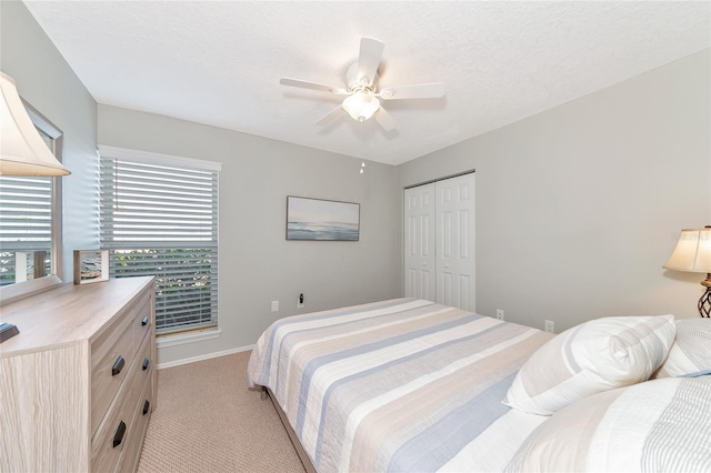 carpeted bedroom with ceiling fan, a closet, and a textured ceiling