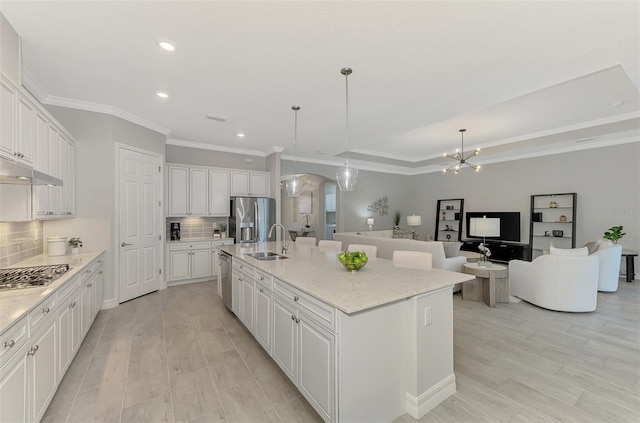 kitchen with white cabinets, appliances with stainless steel finishes, a kitchen island with sink, and hanging light fixtures