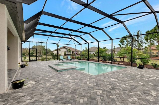 view of swimming pool featuring a hot tub, glass enclosure, and a patio area