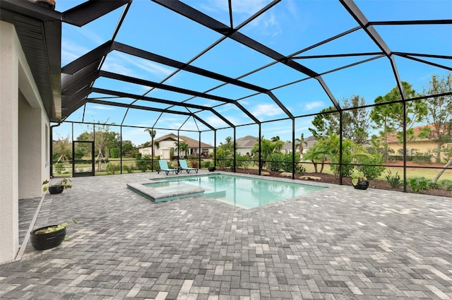 view of swimming pool featuring a hot tub, glass enclosure, and a patio area