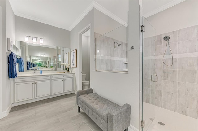 bathroom featuring vanity, toilet, a shower with shower door, and crown molding