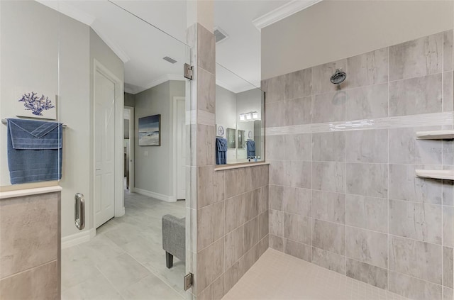 bathroom featuring tile patterned flooring, a tile shower, and crown molding