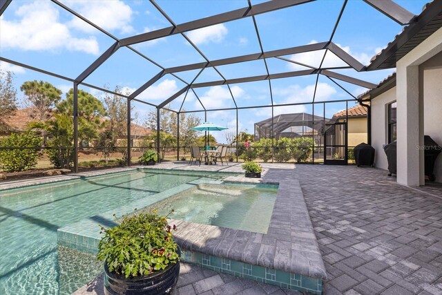 view of pool with grilling area, a patio area, a lanai, and a pool with connected hot tub