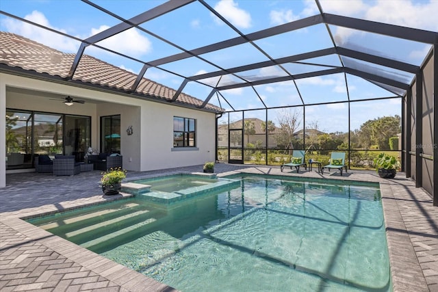 view of swimming pool featuring glass enclosure, a pool with connected hot tub, an outdoor living space, a ceiling fan, and a patio area