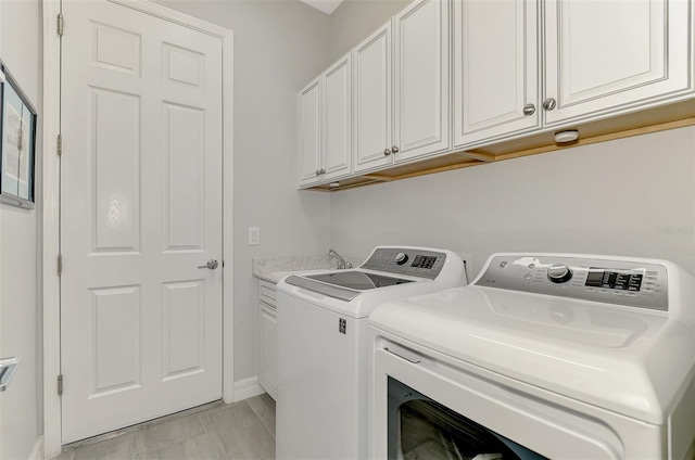 clothes washing area with cabinet space, baseboards, marble finish floor, washer and dryer, and a sink