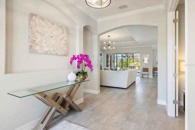 entrance foyer featuring arched walkways, a notable chandelier, crown molding, and baseboards