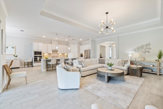 living room with arched walkways, visible vents, an inviting chandelier, a raised ceiling, and crown molding