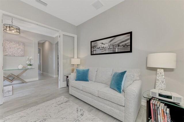 living area featuring arched walkways, wood finished floors, visible vents, and baseboards