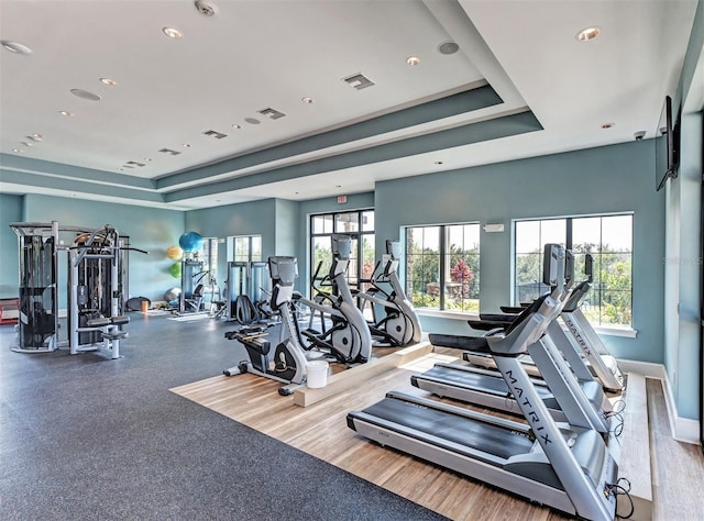 workout area featuring a raised ceiling, visible vents, and baseboards