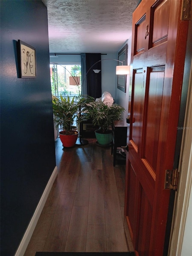 hall with a textured ceiling and dark wood-type flooring