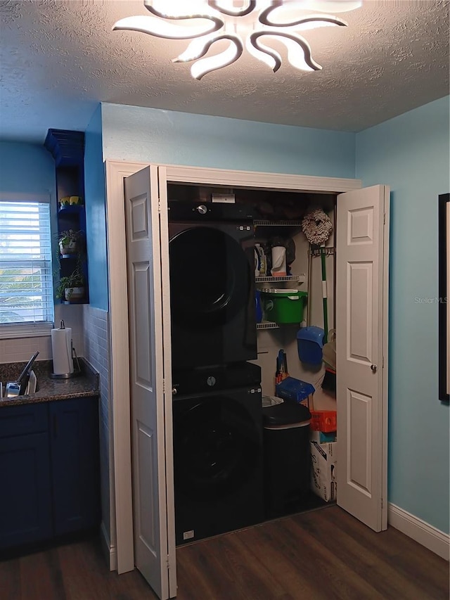 laundry area featuring a textured ceiling, dark hardwood / wood-style floors, and stacked washer / dryer