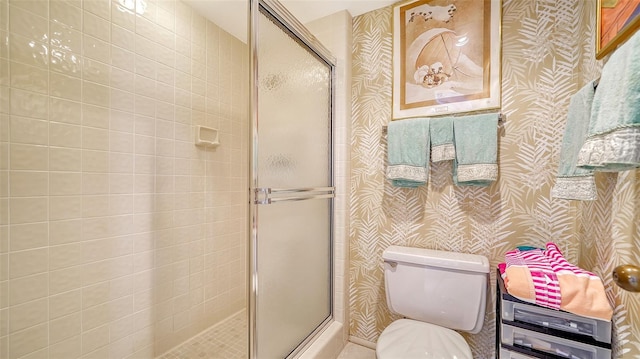 bathroom featuring toilet and a shower with shower door