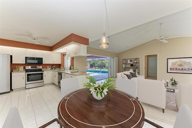 dining area with a textured ceiling, lofted ceiling, light tile patterned floors, and ceiling fan