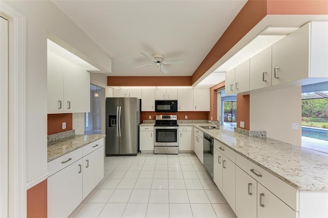 kitchen with light tile patterned floors, appliances with stainless steel finishes, white cabinetry, a ceiling fan, and a sink