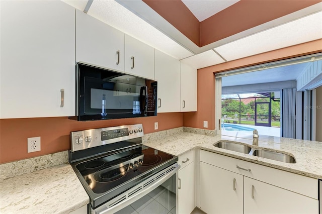 kitchen with black microwave, light stone countertops, electric stove, white cabinets, and a sink