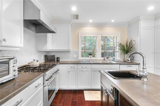 kitchen with double oven range, sink, wall chimney exhaust hood, dark hardwood / wood-style flooring, and white cabinetry