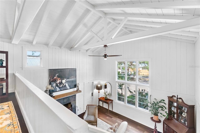 living room with lofted ceiling with beams, ceiling fan, dark wood-type flooring, and wooden walls