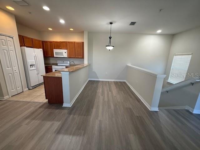 kitchen featuring white appliances, sink, hanging light fixtures, hardwood / wood-style flooring, and kitchen peninsula