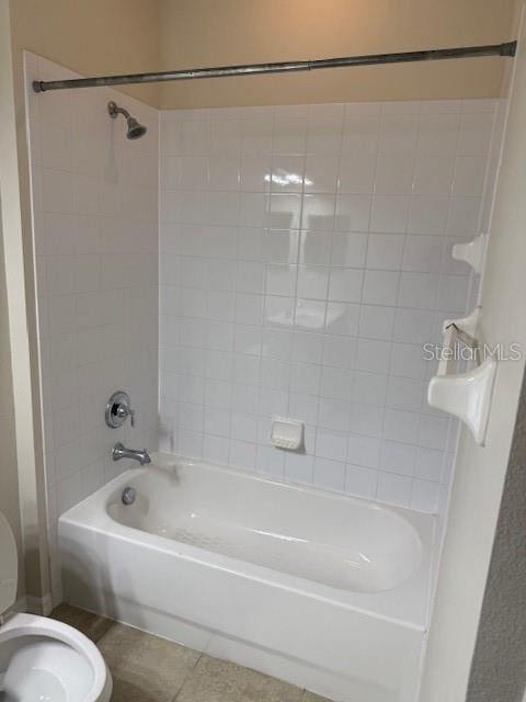 bathroom featuring tile patterned floors, toilet, and tiled shower / bath