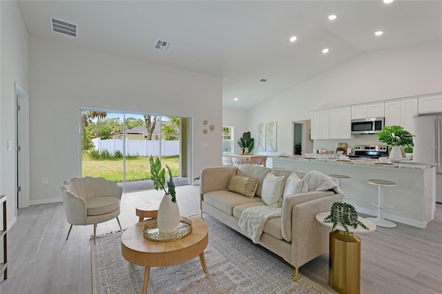 living room featuring light wood-type flooring and high vaulted ceiling