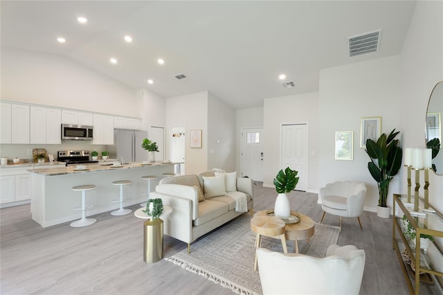 living room with high vaulted ceiling and light hardwood / wood-style flooring